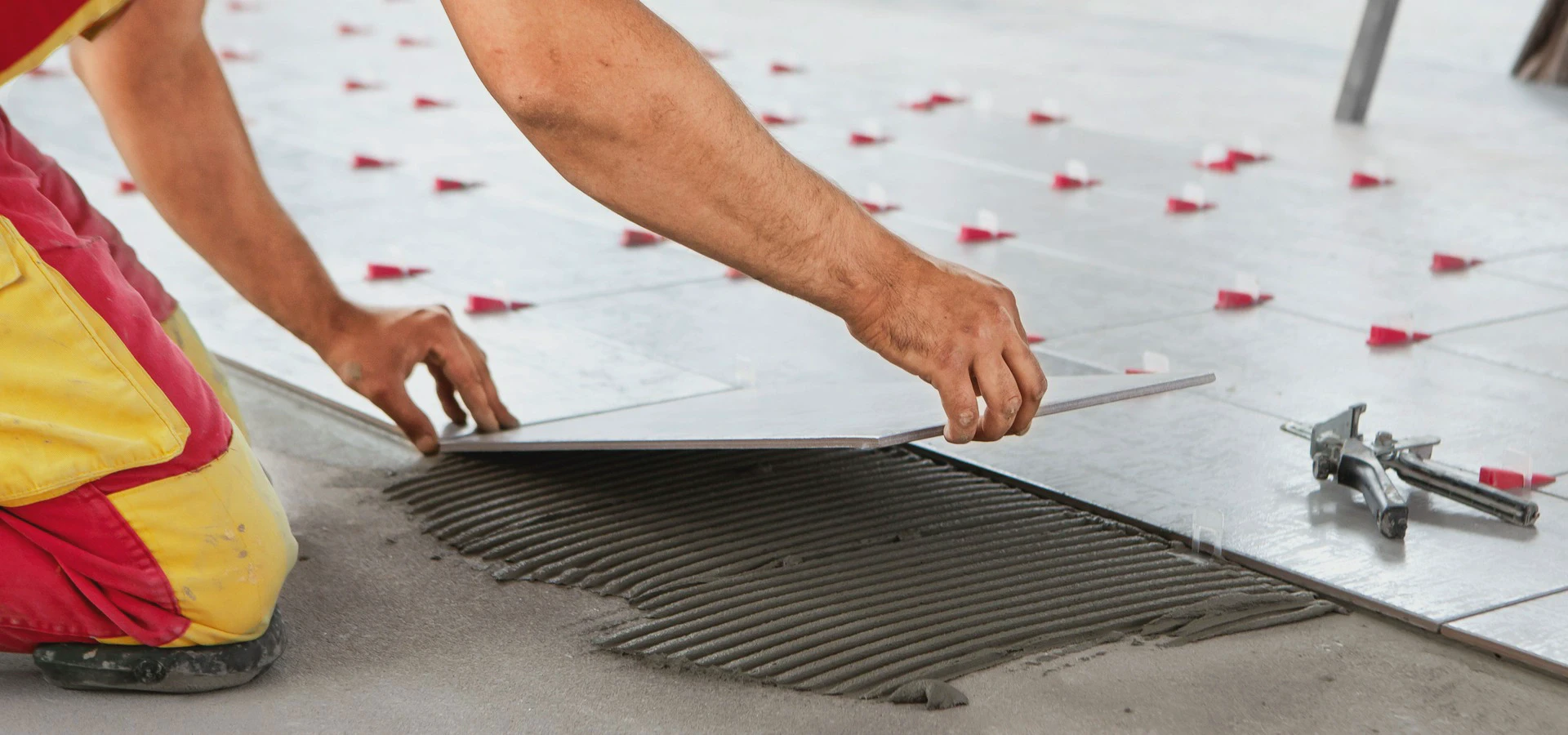 Układanie płytki ceramicznej na&nbsp;warstwie kleju podczas prac glazurniczych